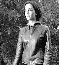 a woman in a leather jacket walks through a path